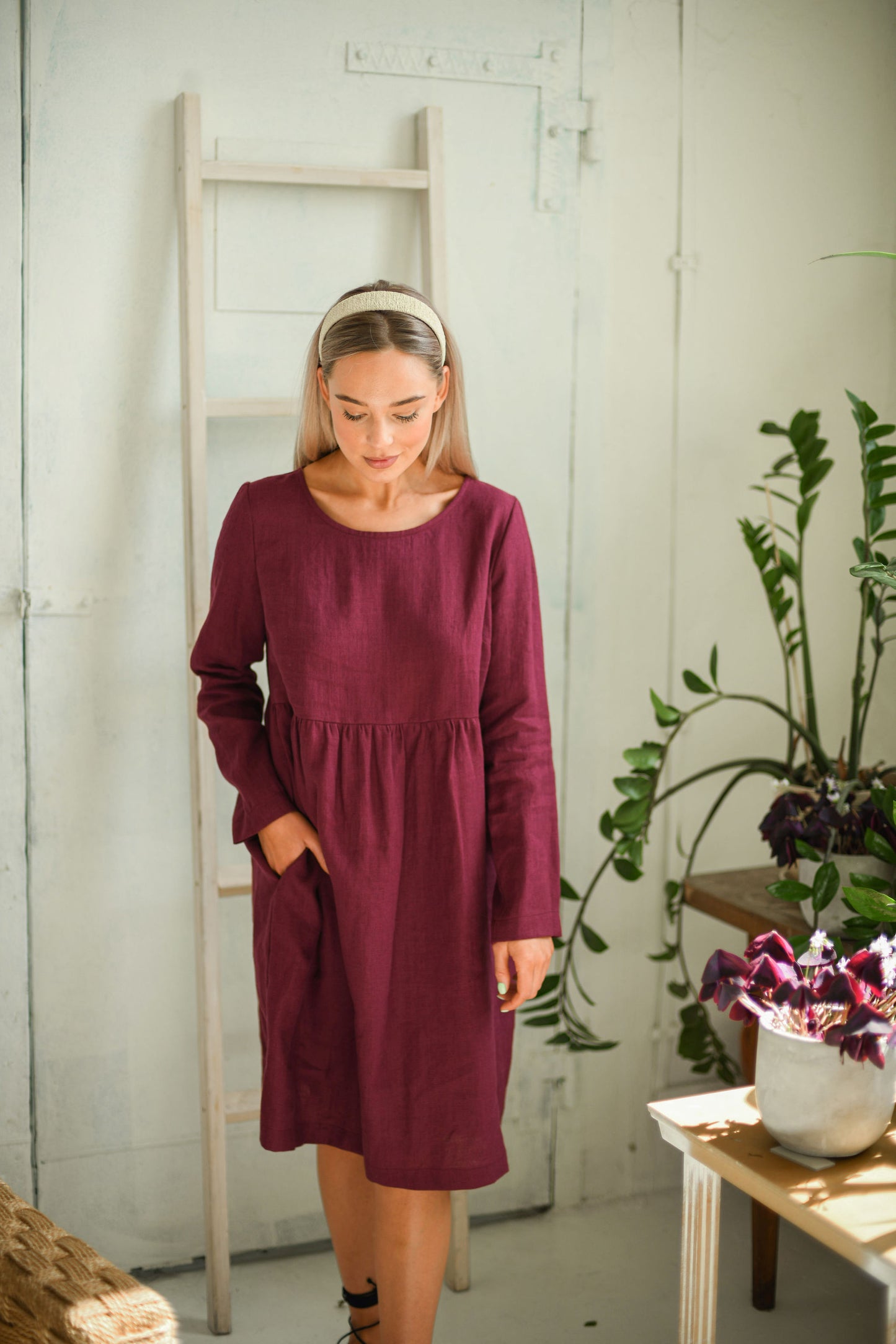 Dusty raspberry linen dress standing calmly indoors full-body showing relaxed silhouette, handmade linen dress slow fashion