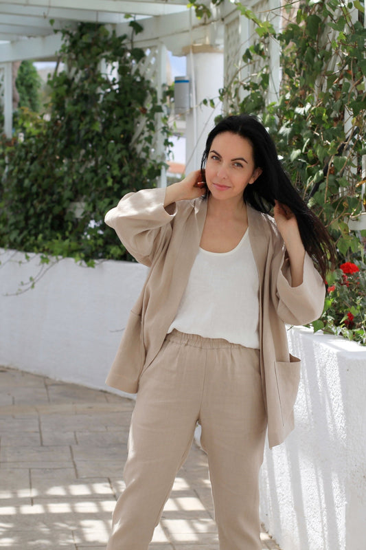Woman in beige outfit standing outdoors with greenery in the background