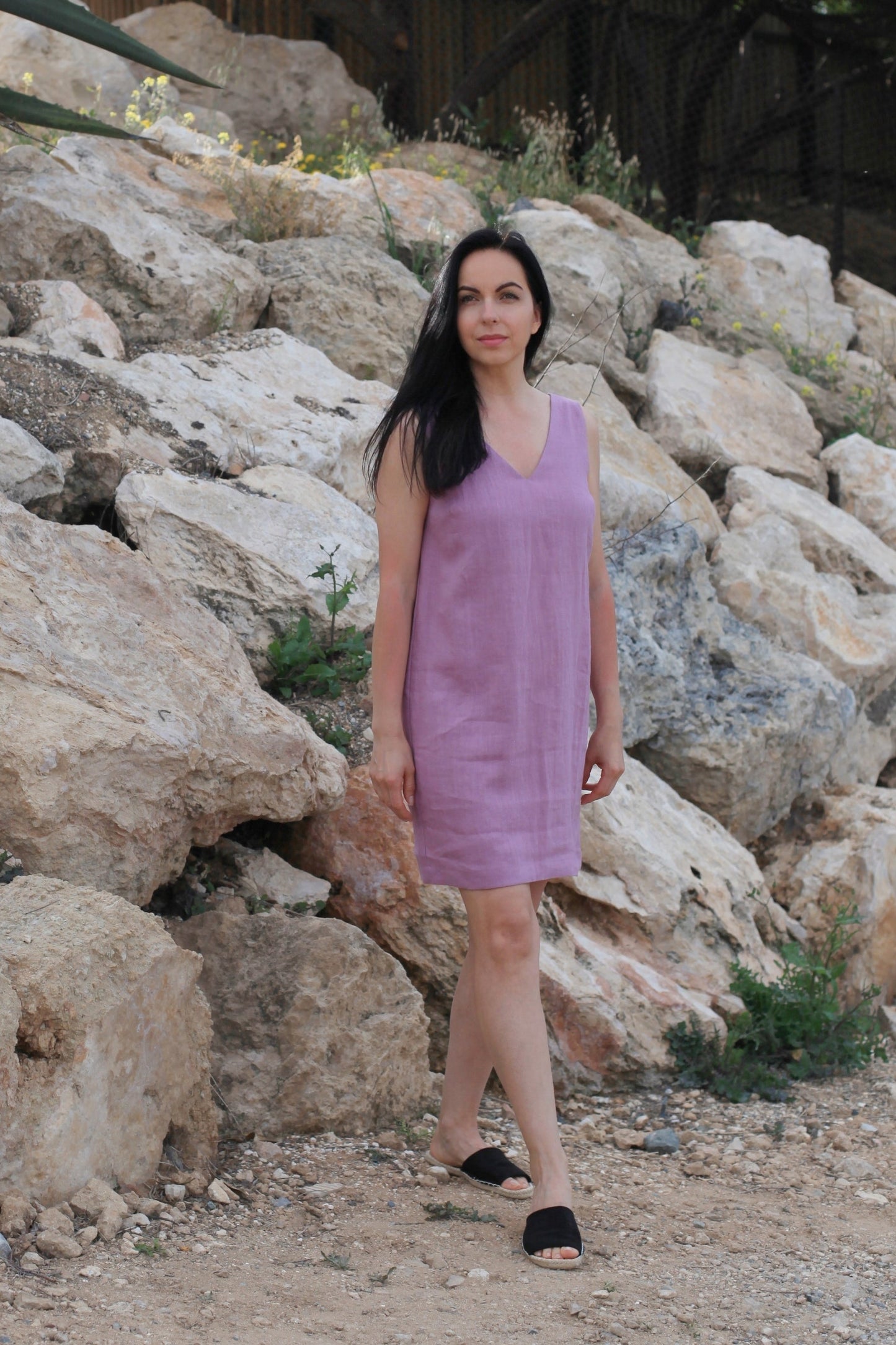 Woman in a purple dress standing in front of large rocks