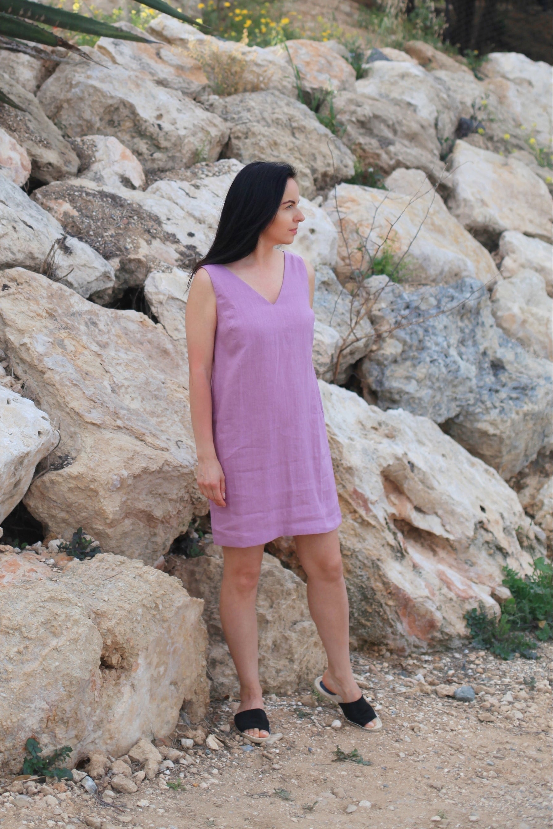 Woman in a purple dress standing among large rocks outdoors