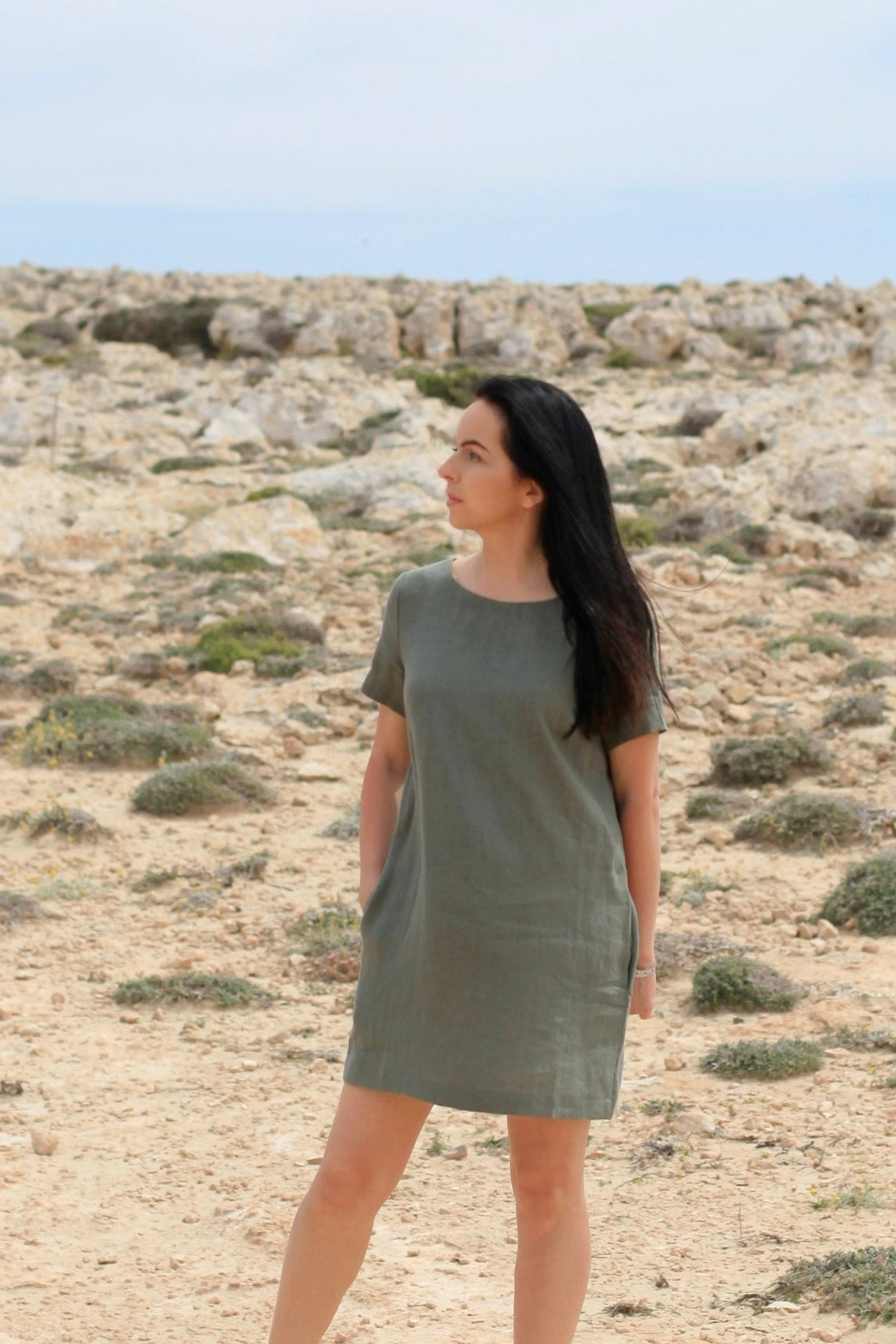 Woman in a green dress standing in a desert landscape