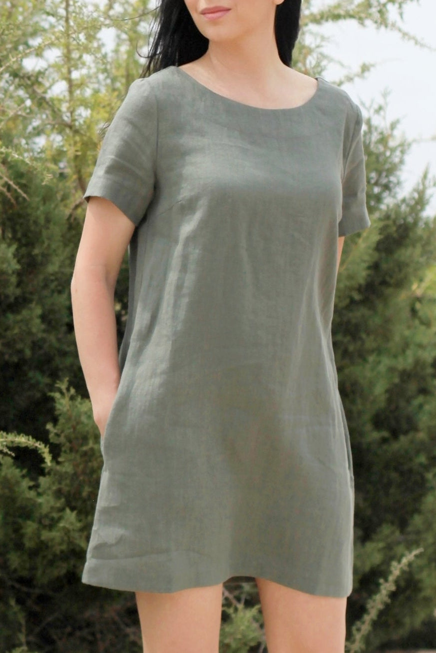 Woman wearing a green dress standing in front of green bushes