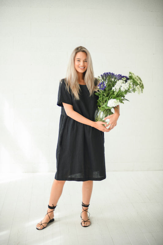 Alba black oversized linen dress front full body studio view holding flowers handmade linen dress slow fashion