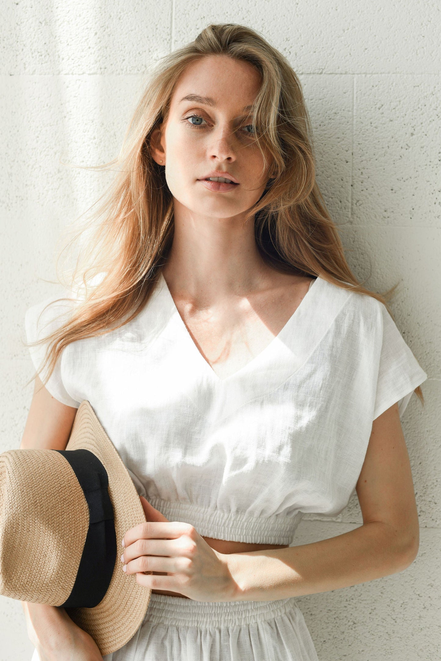 Half body front view of a linen skirt with a side slit and relaxed gathered waist.