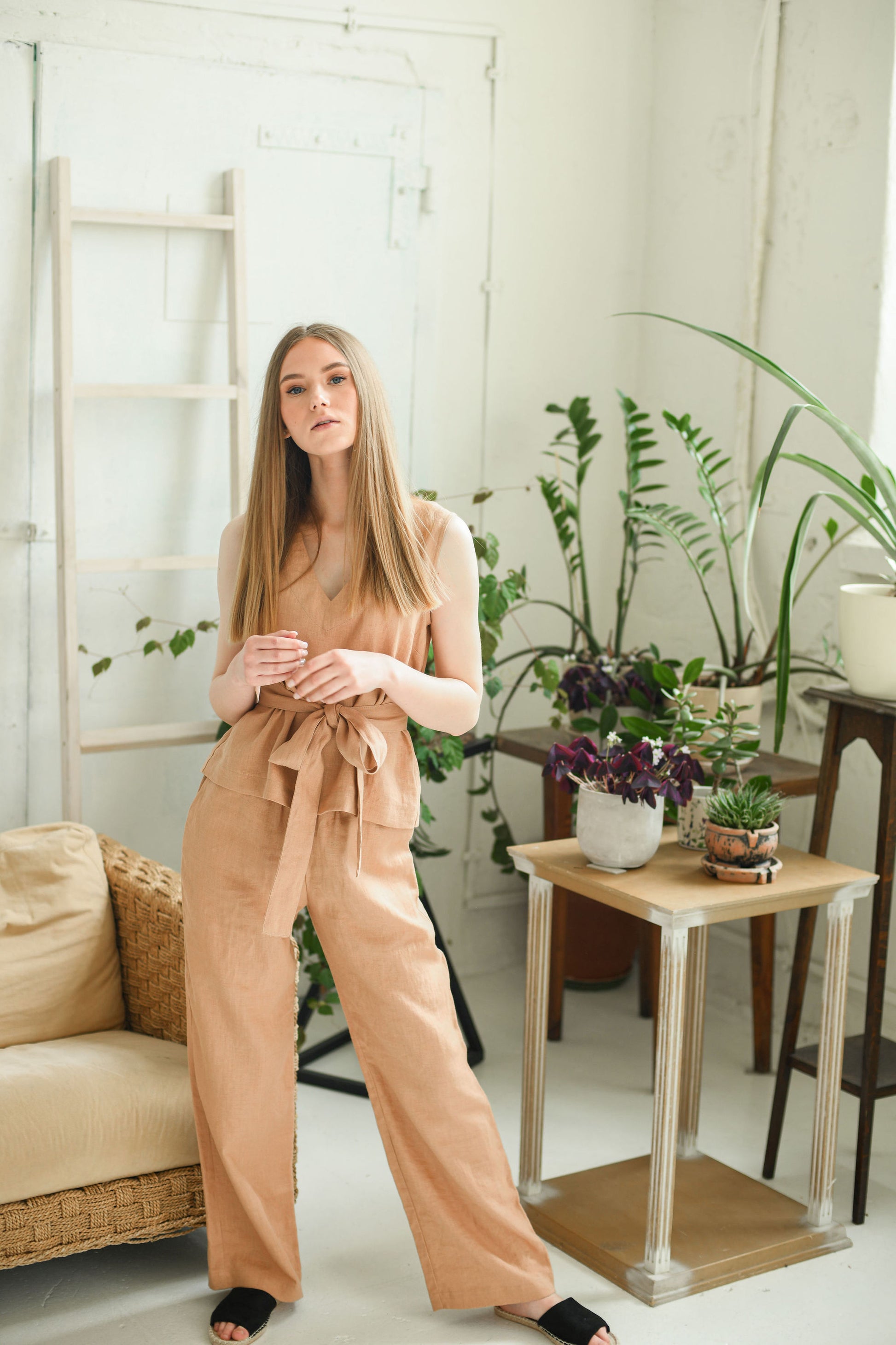 Caramel brown linen pants three-quarter side pose indoors showing drape, handmade linen pants slow fashion