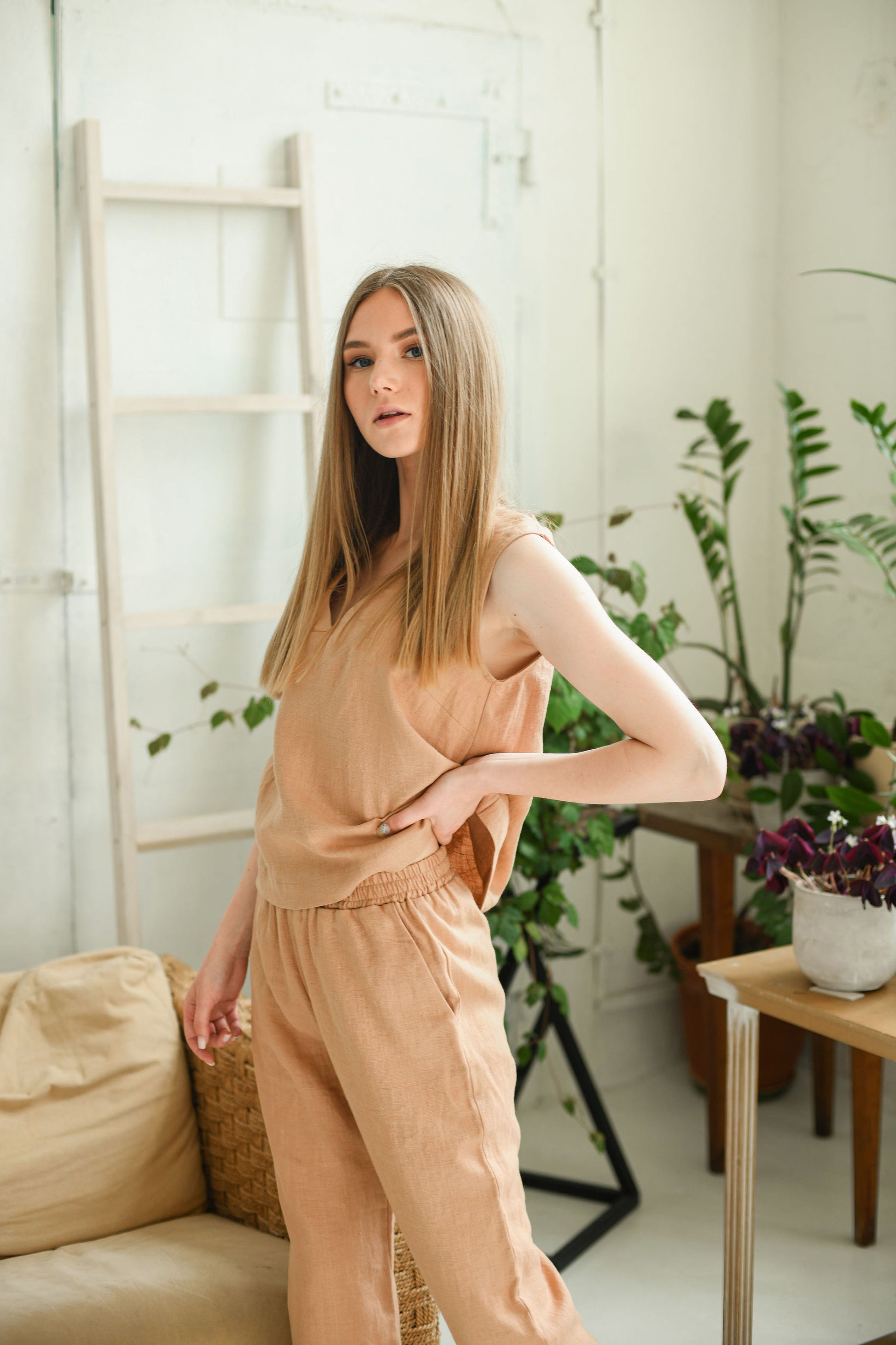 Caramel brown linen pants indoor pose showing relaxed silhouette, handmade linen pants slow fashion