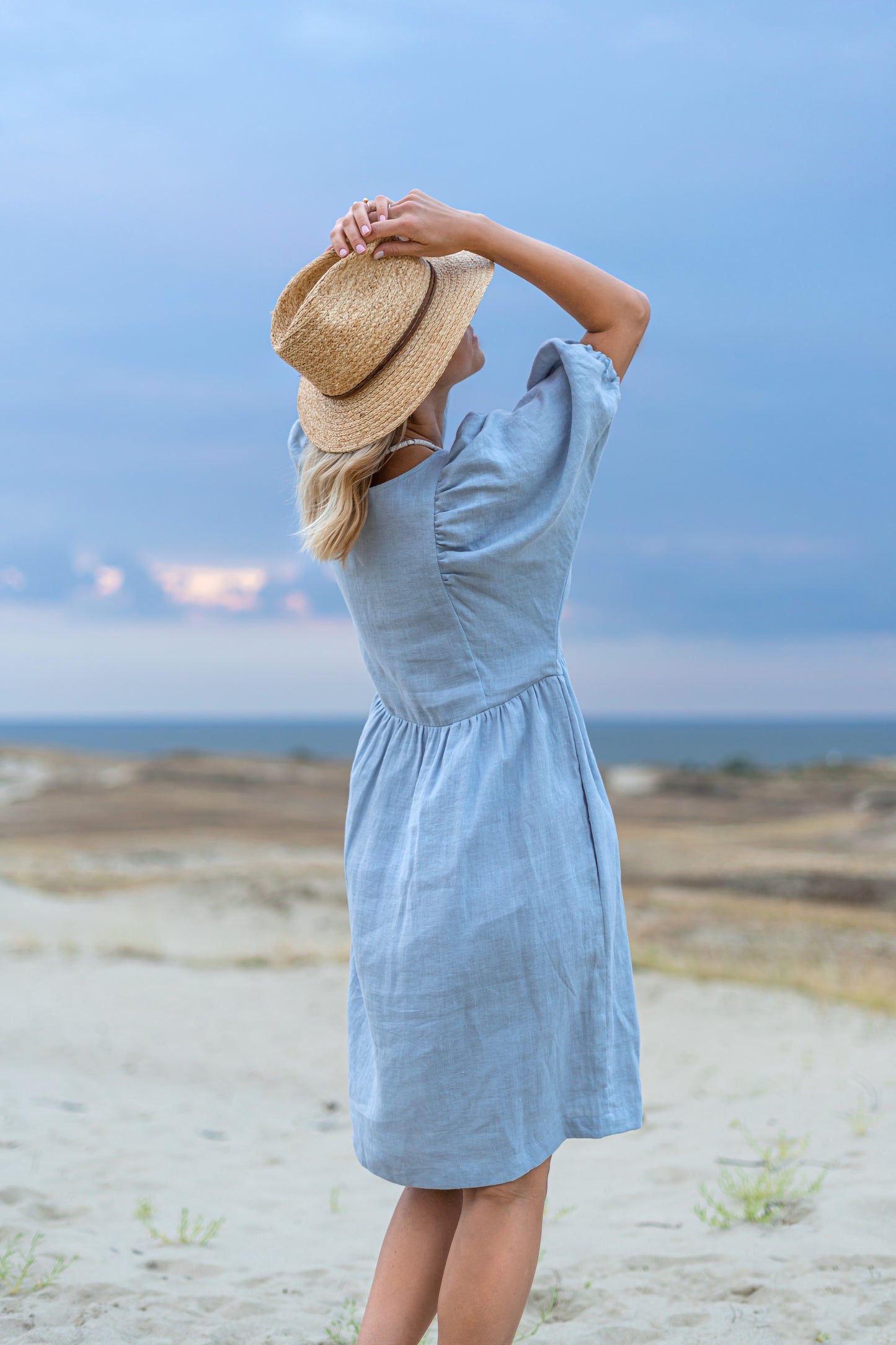 Light blue linen dress back view on beach showing loose-fit drape, handmade linen dress slow fashion