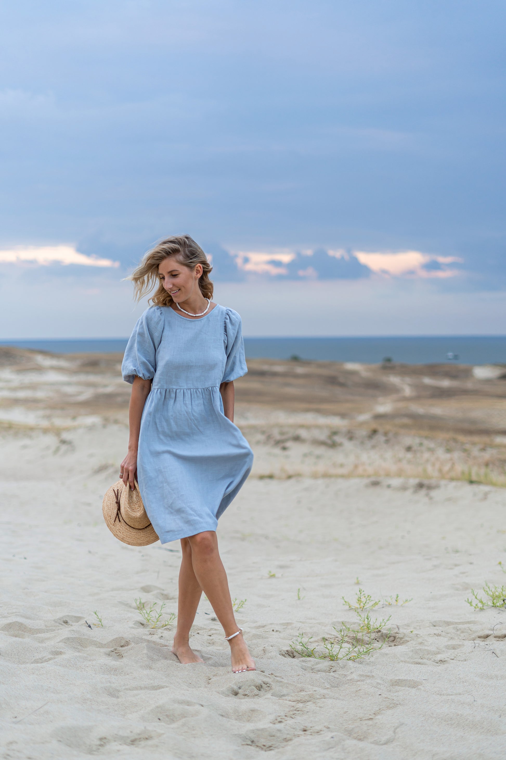 Light blue linen dress walking on beach showing relaxed movement and drape, handmade linen dress slow fashion