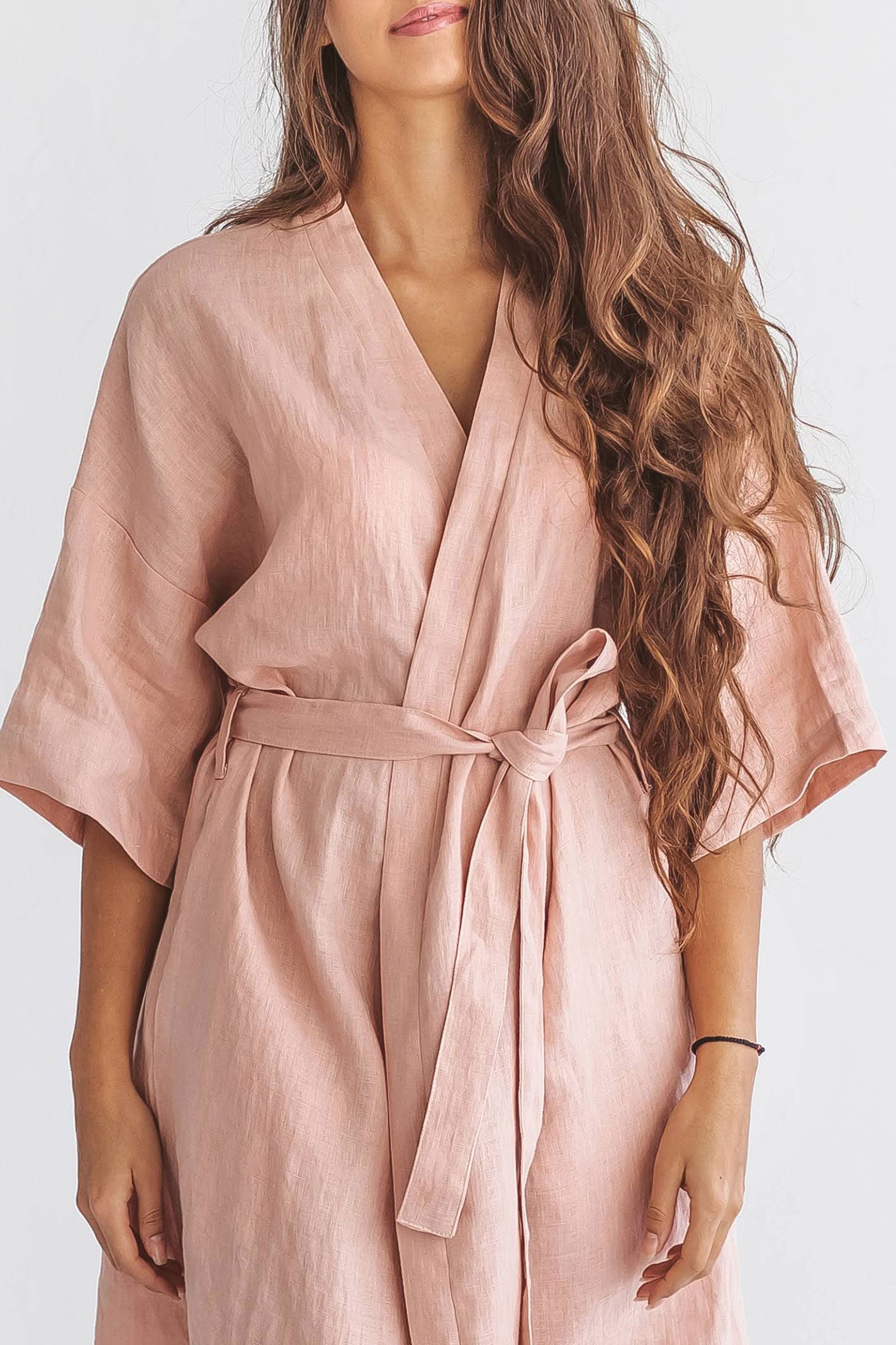 Pastel pink linen robe front close-up with belt tied at waist showing wrap detail, handmade linen robe slow fashion