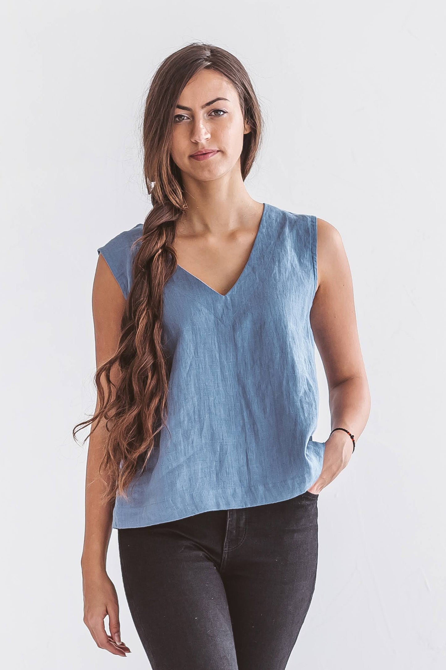 Sleeveless linen top with relaxed V-neck silhouette, shown on model in natural light, sustainable slow fashion clothing