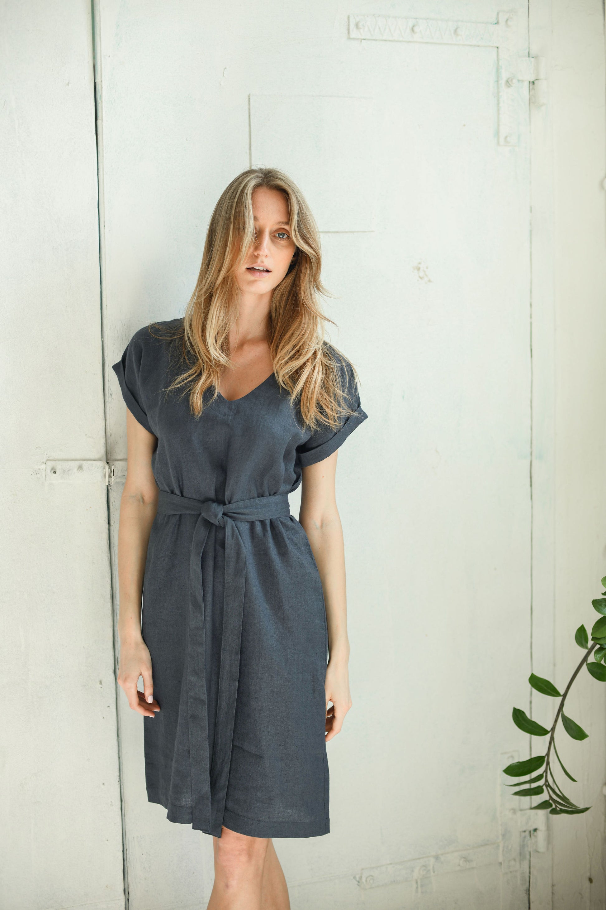 Front view of linen midi dress with a tied belt, relaxed V-neckline, and softly extended sleeves.