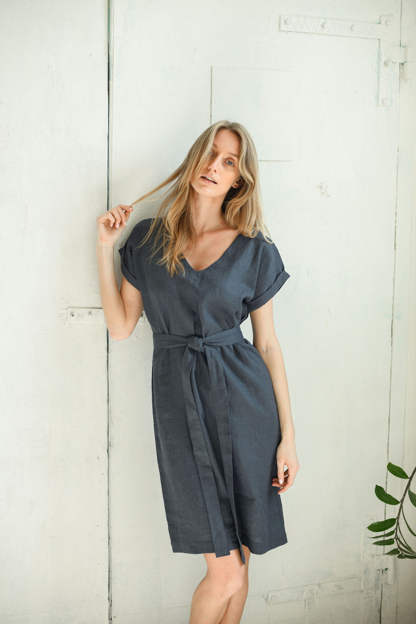 Linen midi dress with a tied waist belt captured in gentle movement, showing the fluid drape and relaxed fit.