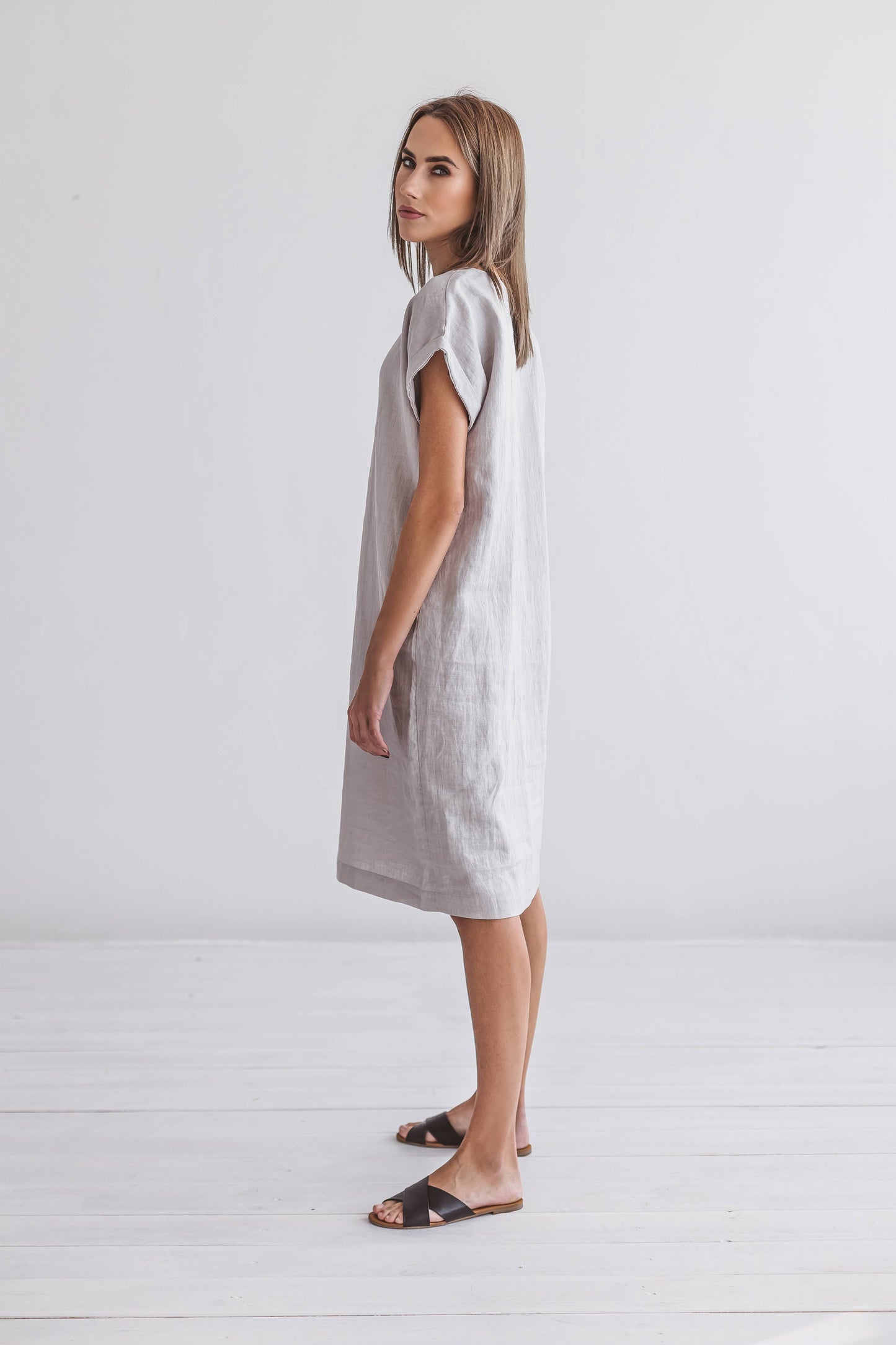 Front view of linen midi dress styled next to a chair, featuring a straight, relaxed cut.
