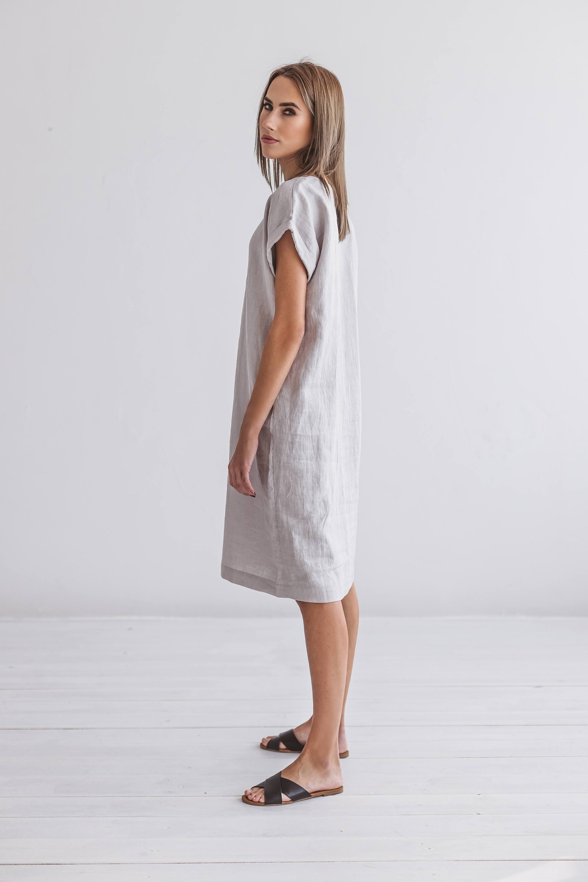Front view of linen midi dress styled next to a chair, featuring a straight, relaxed cut.