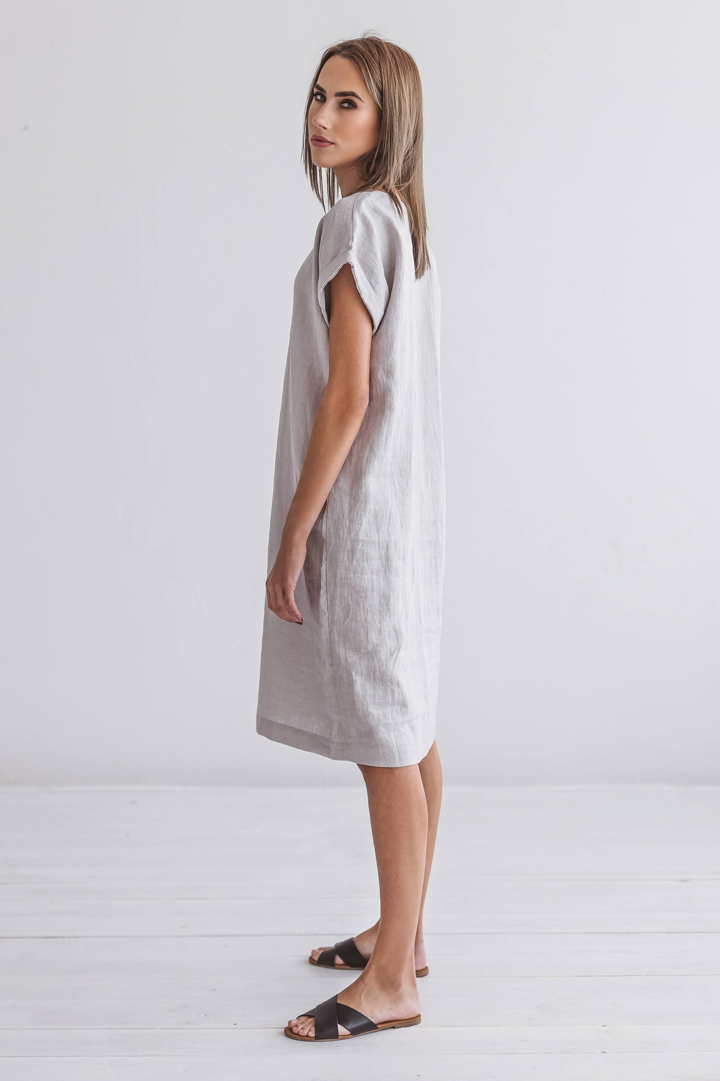 Side angle of linen midi dress beside a chair, showing the gentle drape and effortless silhouette.