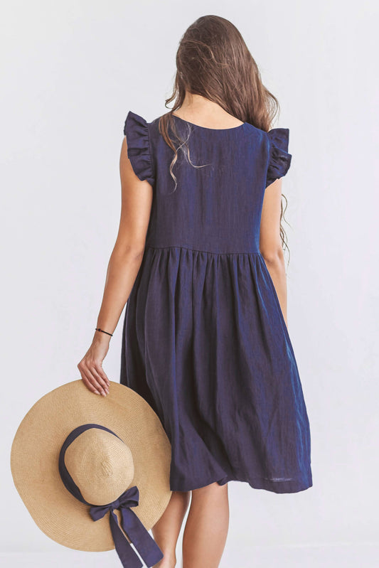 Side view of linen dress with flowing gathered fabric and light ruffled shoulder detailing.