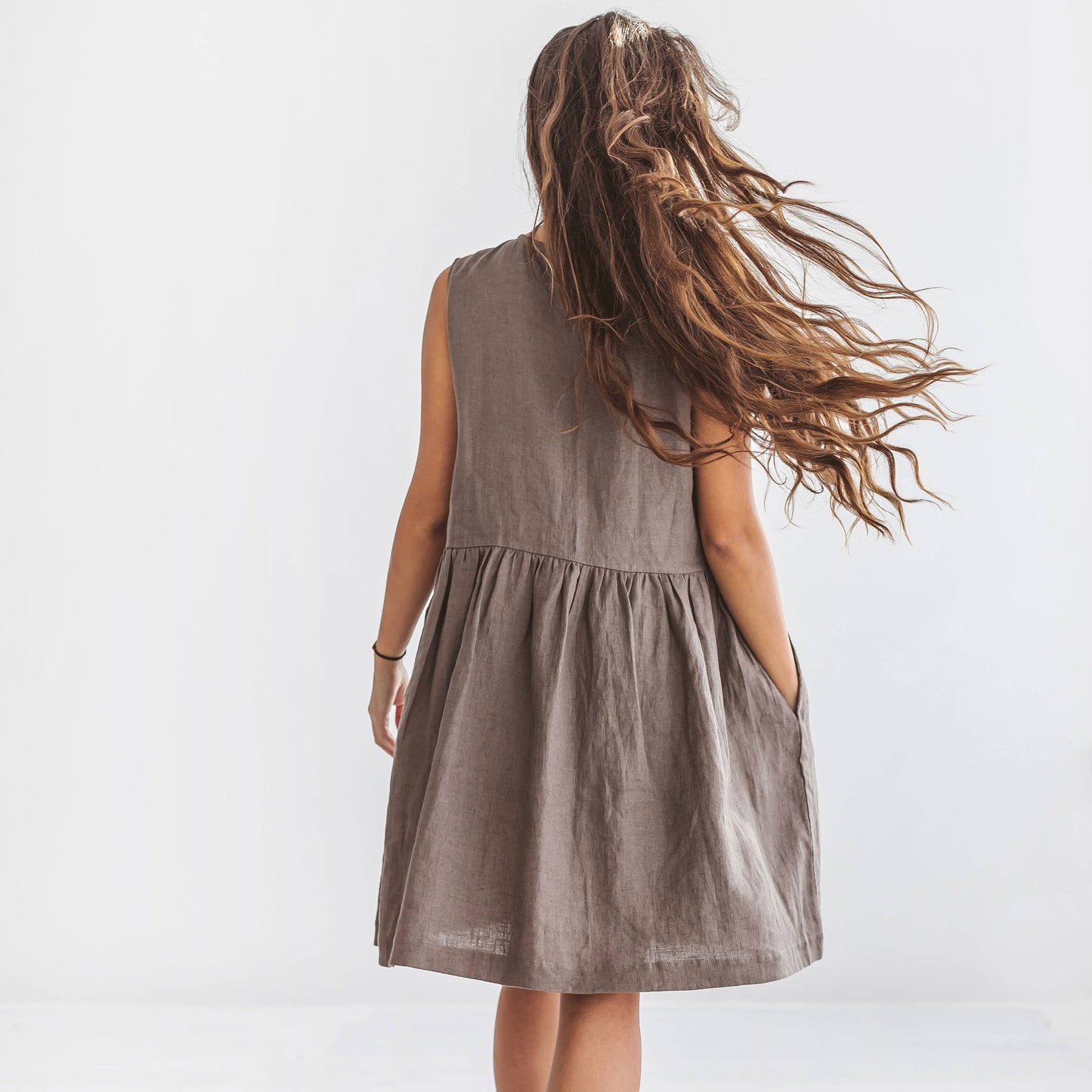 Back view of the Kelly linen dress in beige showing voluminous A-line shape and relaxed movement