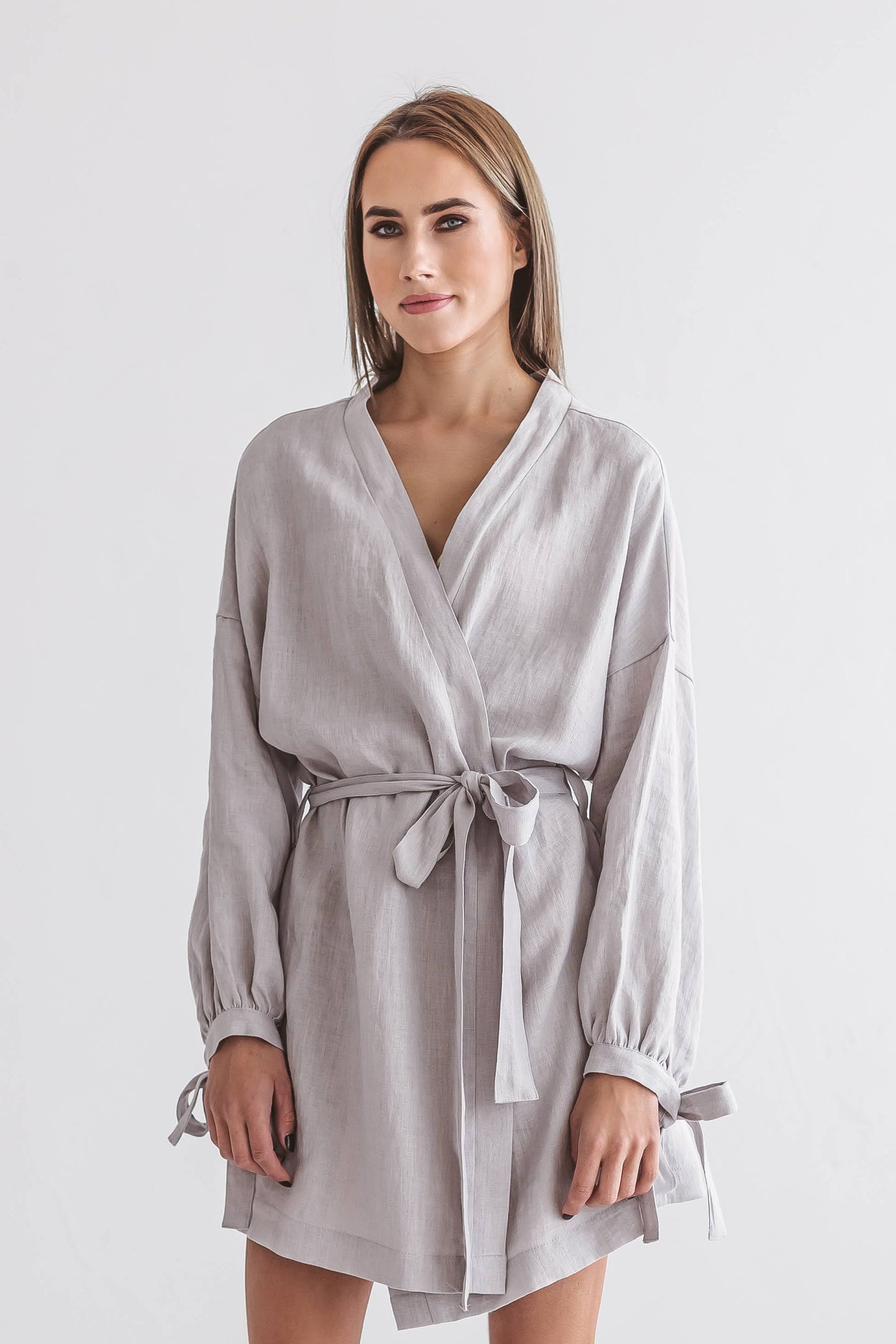 Woman adjusting the sleeves of a relaxed-fit linen kimono robe, handmade linen clothing slow fashion