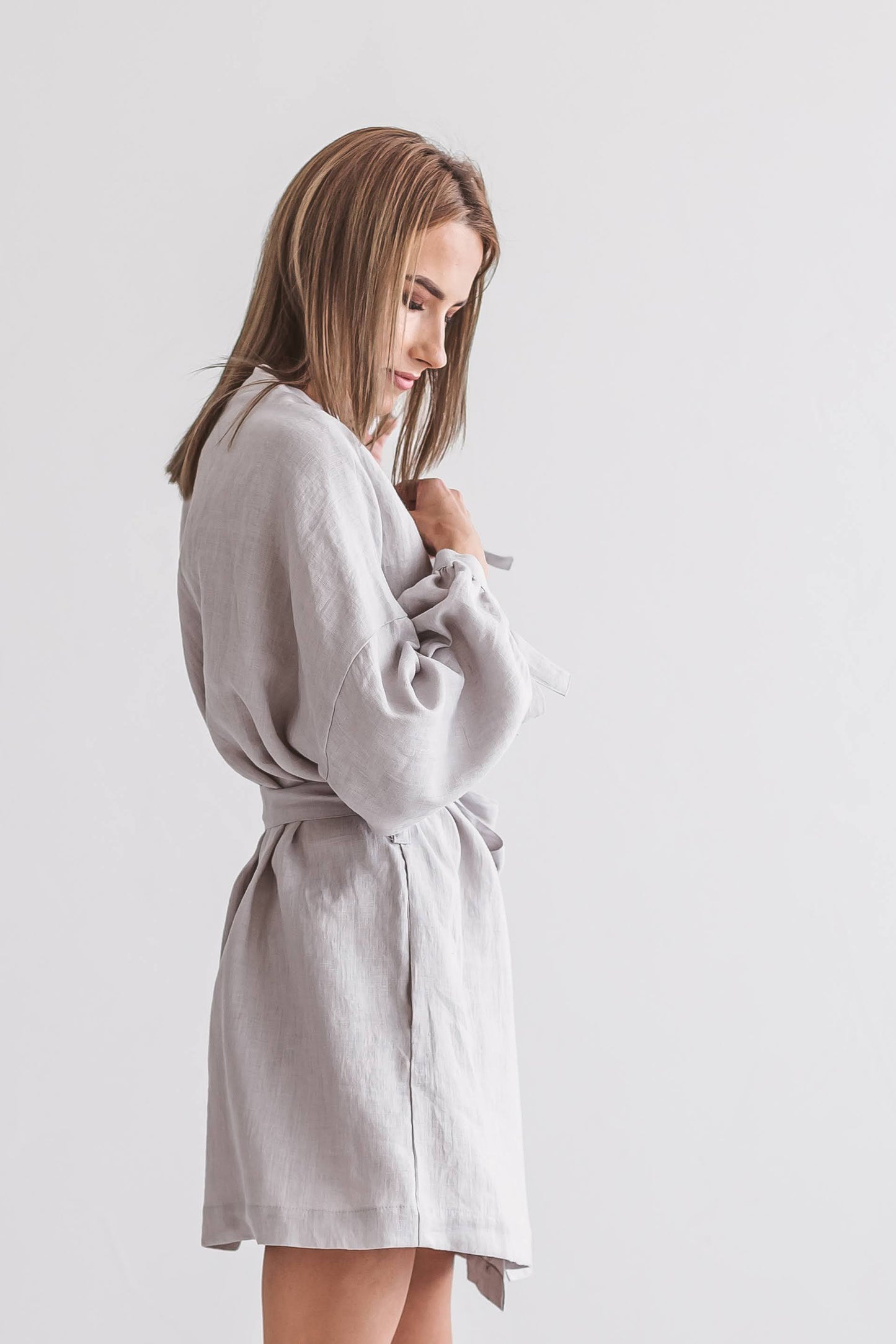 Side view of a woman in a linen kimono robe with a belt tie, handmade linen clothing slow fashion