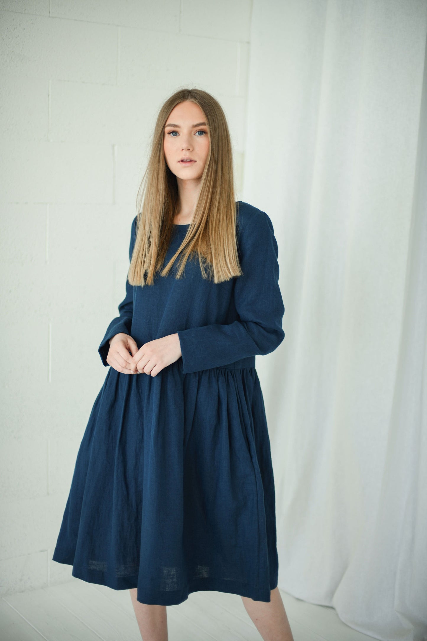 Side view of model in relaxed long-sleeve linen dress