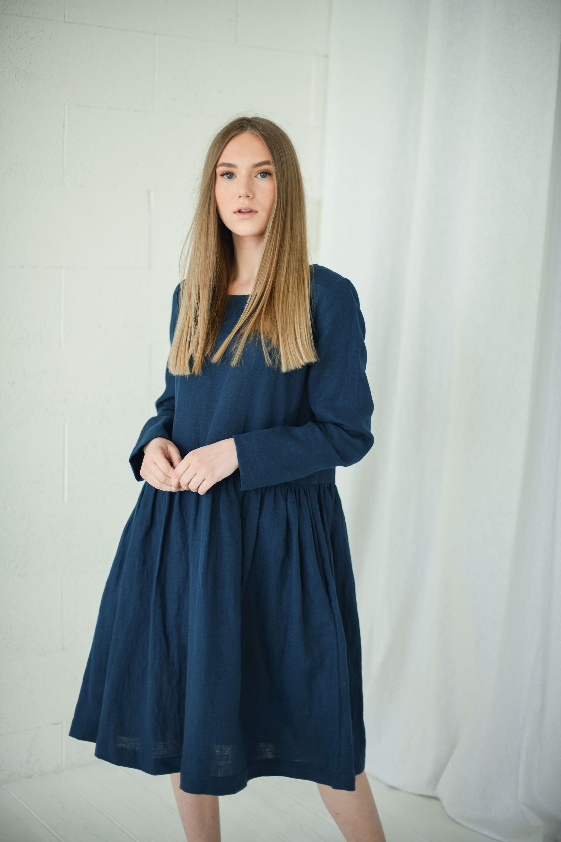 Side view of model in relaxed long-sleeve linen dress