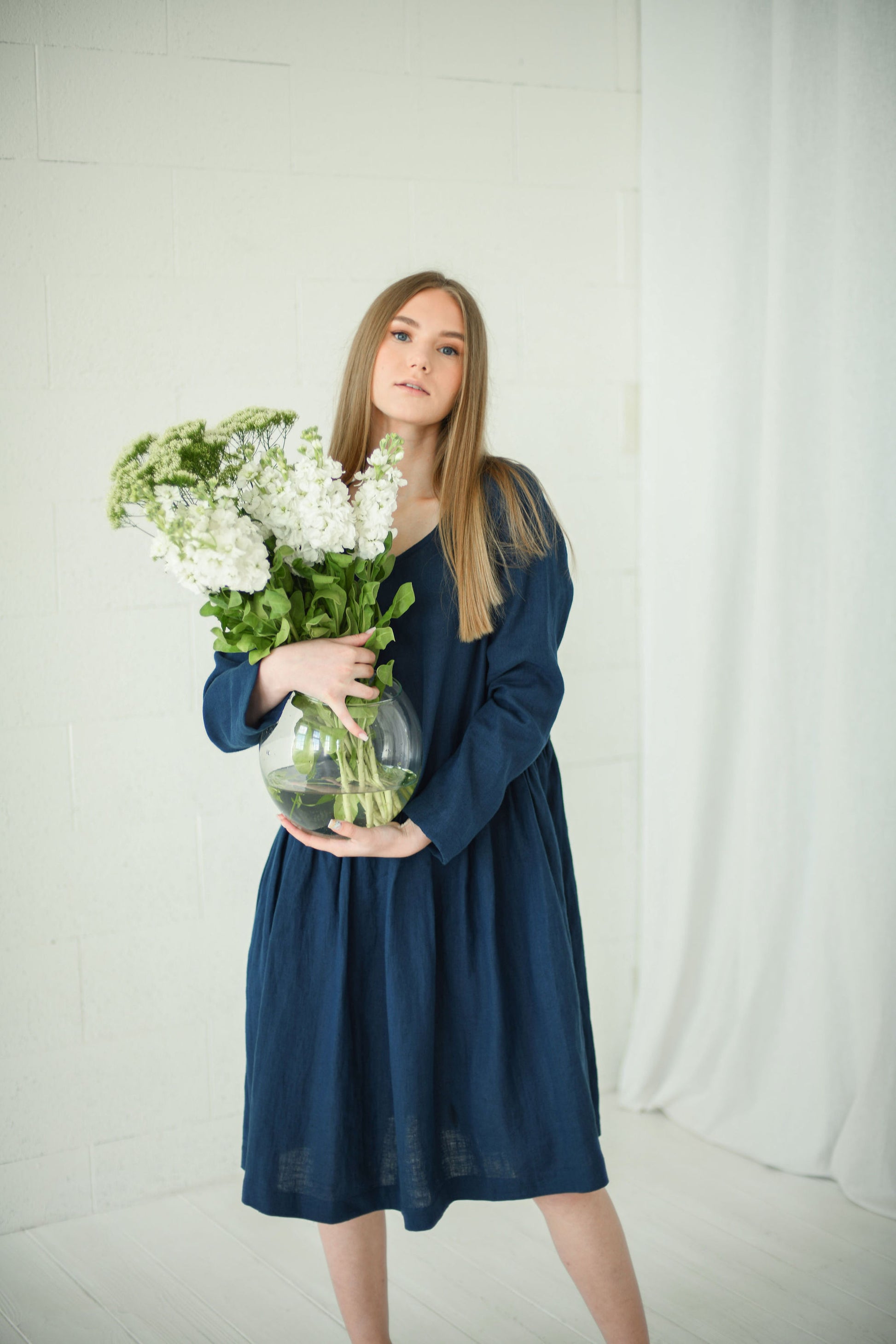 Model holding flowers while wearing relaxed long-sleeve linen dress