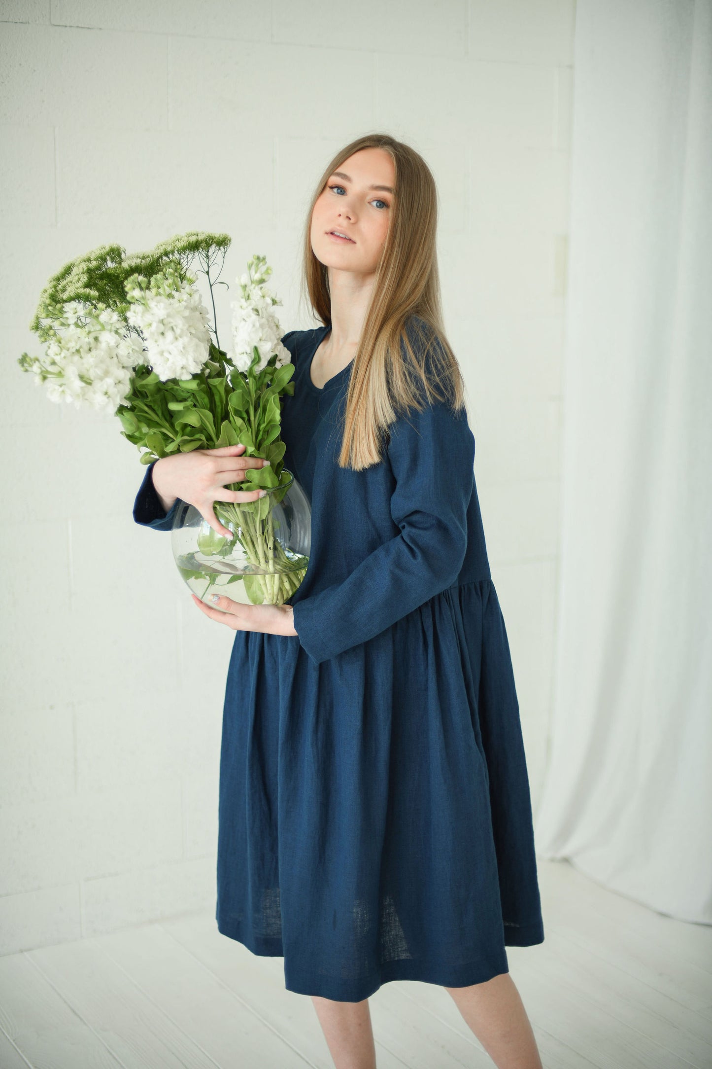 Model holding flowers in a relaxed long-sleeve linen dress