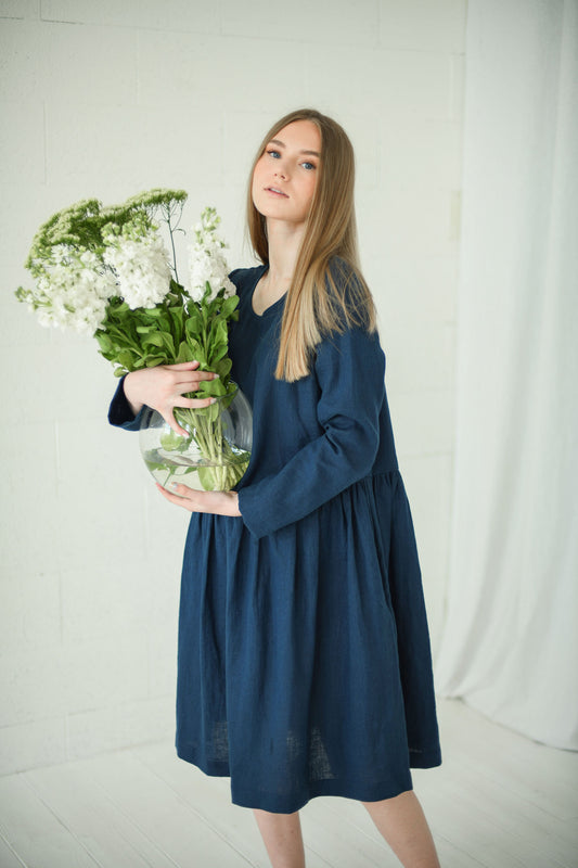 Model holding flowers in a relaxed long-sleeve linen dress