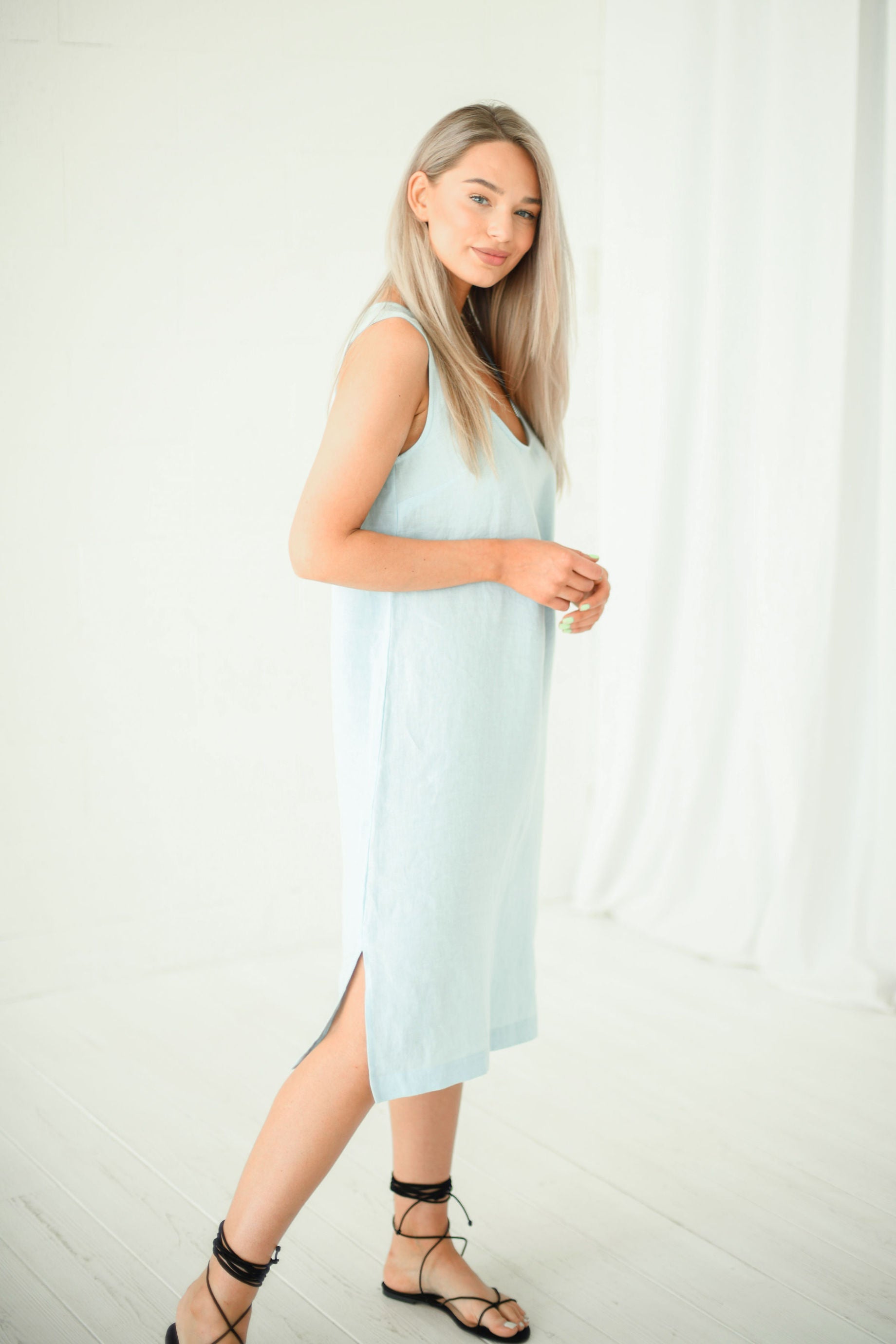Side view of light blue linen midi dress styled with hat, handmade linen dress slow fashion