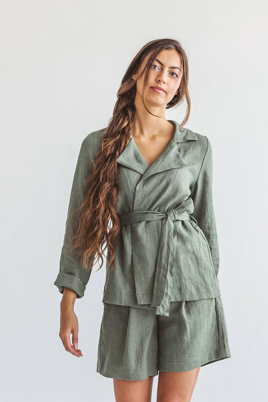 Linen jacket styled with belt, model standing in studio, looking