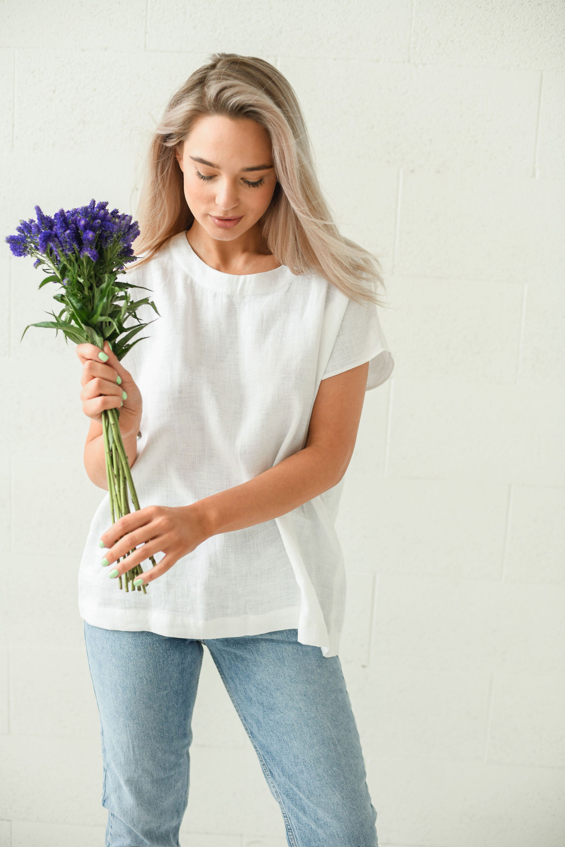 White linen top close-up view holding flowers relaxed fit, handmade linen top slow fashion