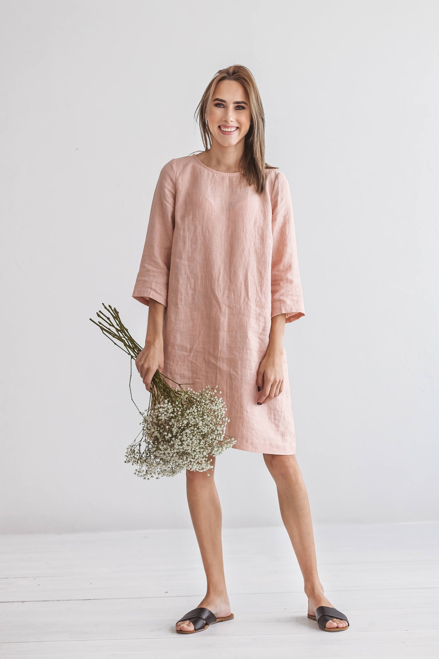 Woman wearing Melinda linen dress, front view, holding flowers