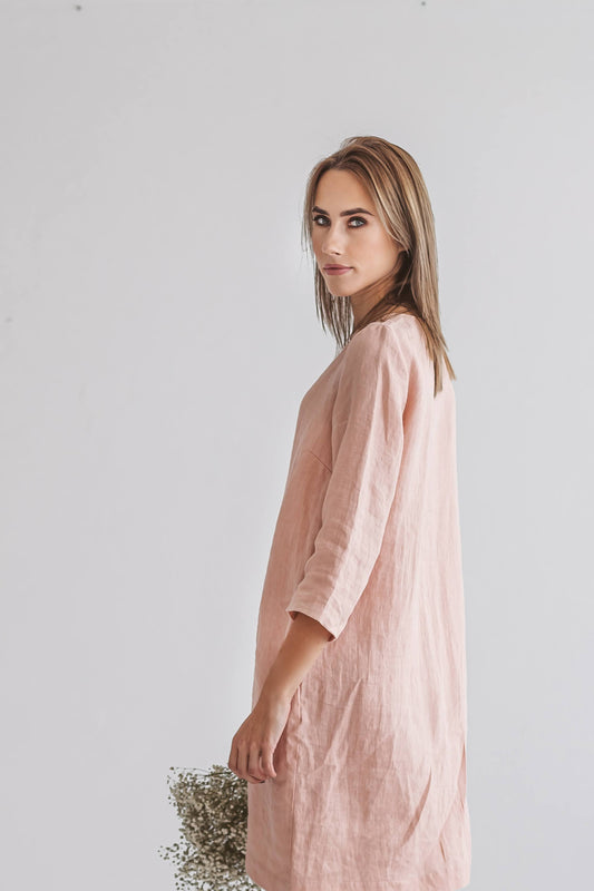 Woman wearing Melinda linen dress, side view, standing with flowers