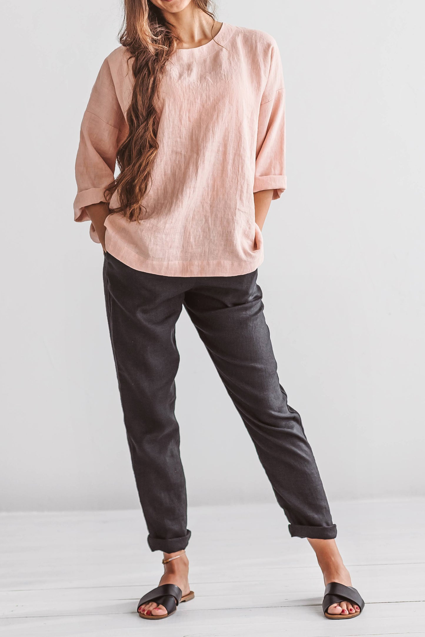 Black linen pants side turning pose in natural light studio, handmade linen pants slow fashion