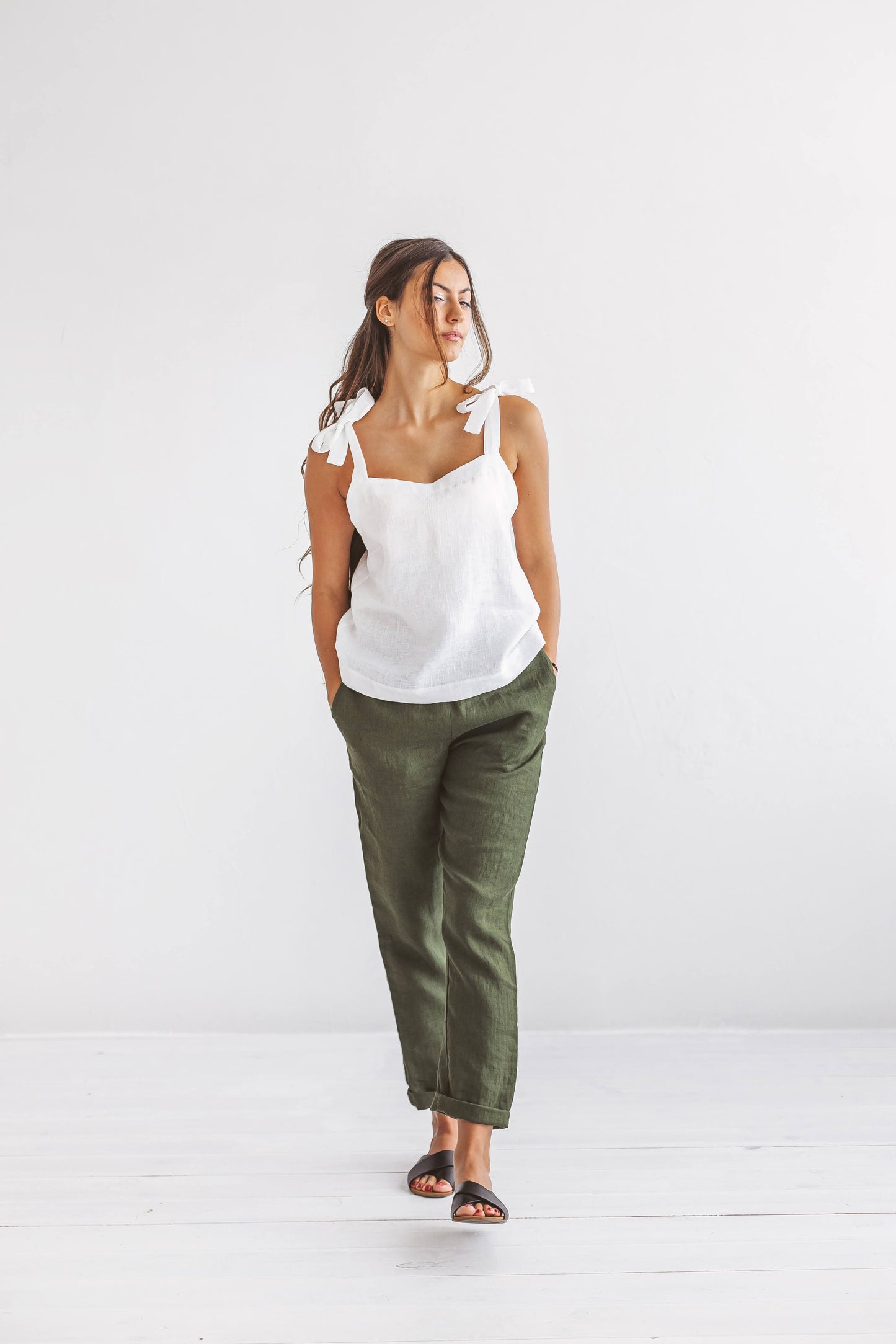 Forest green linen pants side front walking pose in studio, handmade linen pants slow fashion