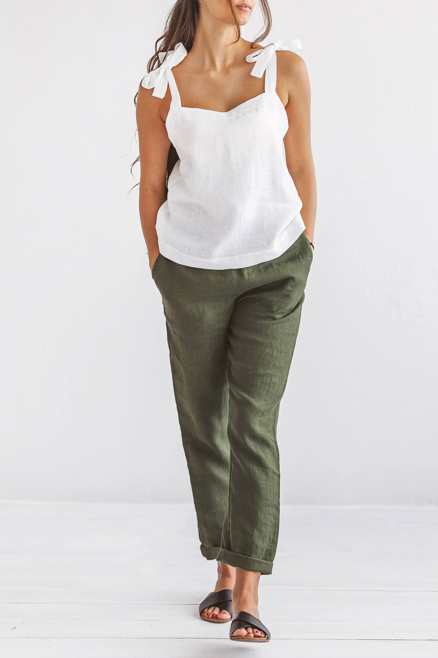 Forest green linen pants studio pose with hands in pockets, handmade linen pants slow fashion