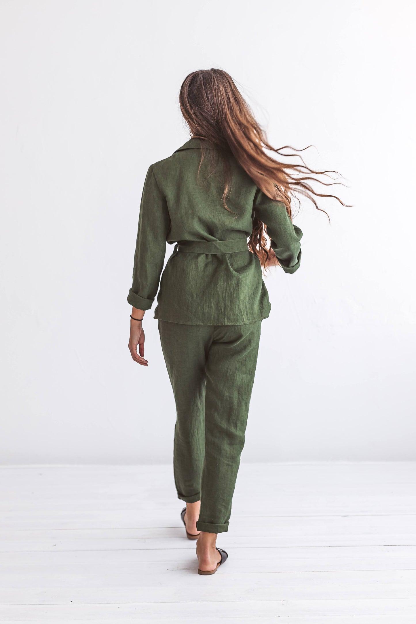 Forest green linen pants walking pose back view showing airy relaxed movement, handmade linen pants slow fashion