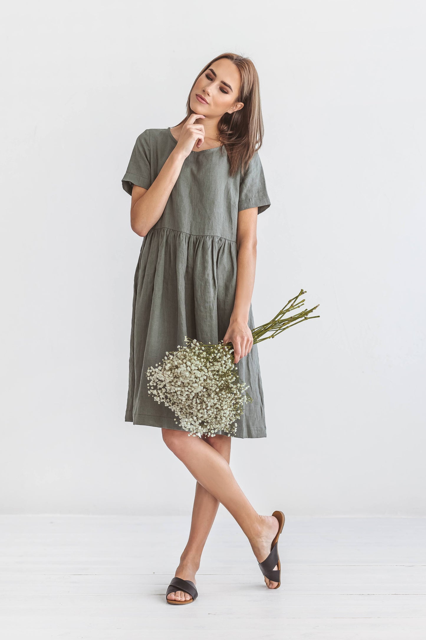 Khaki linen dress standing forward pose in natural light studio, handmade linen dress slow fashion