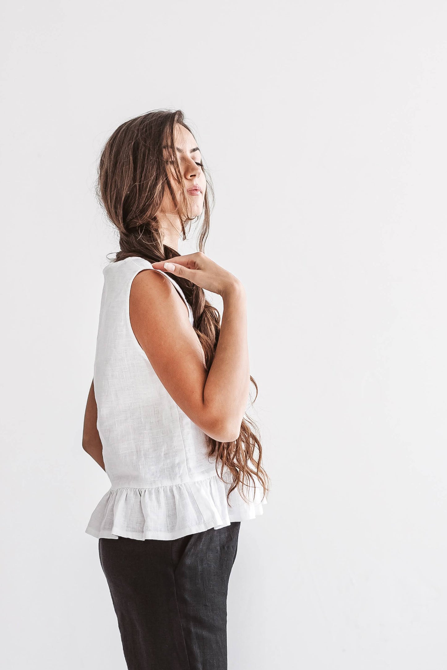 White linen top half-profile view showing soft drape and ruffle hem, handmade linen top slow fashion