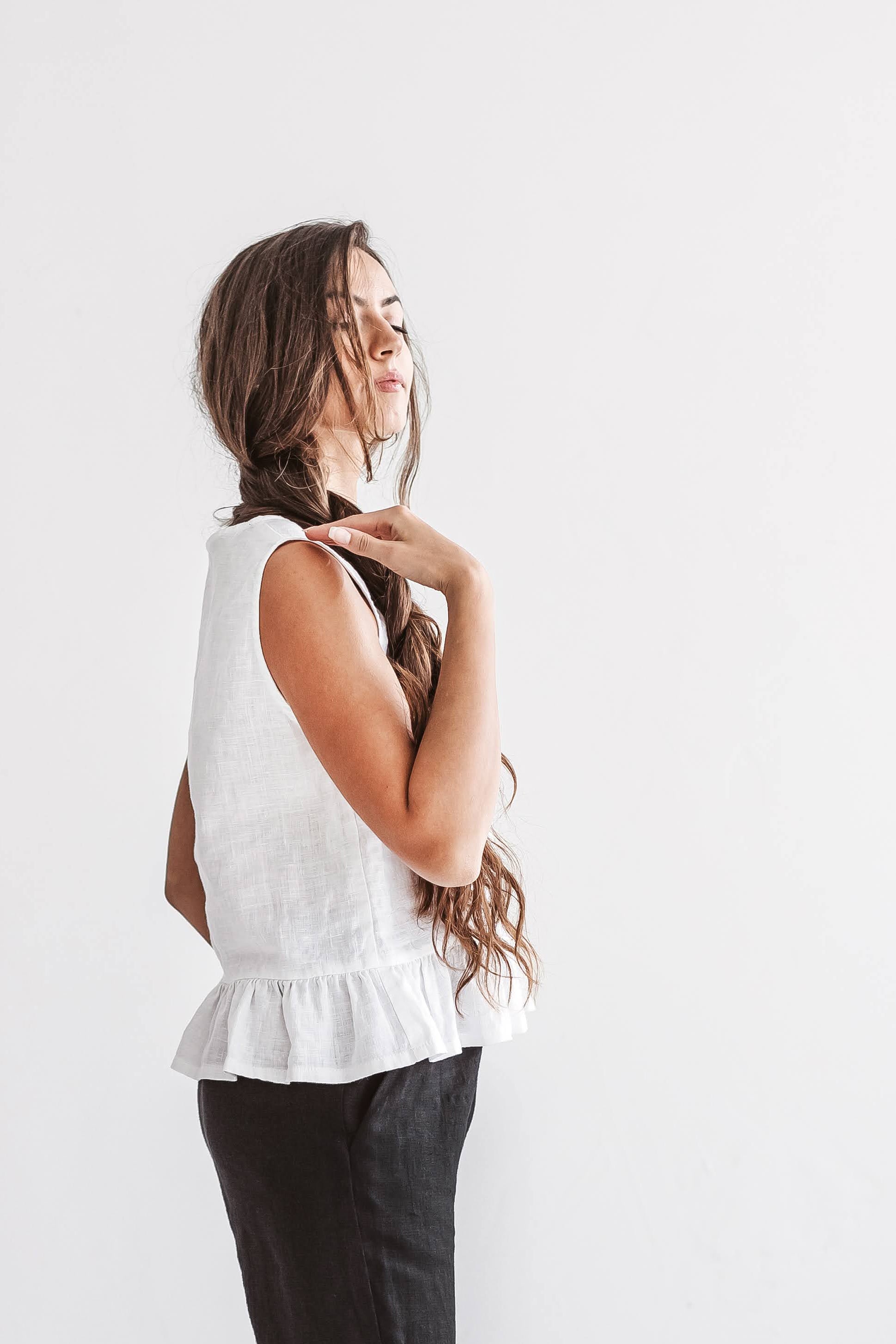 White linen top half-profile view showing soft drape and ruffle hem, handmade linen top slow fashion