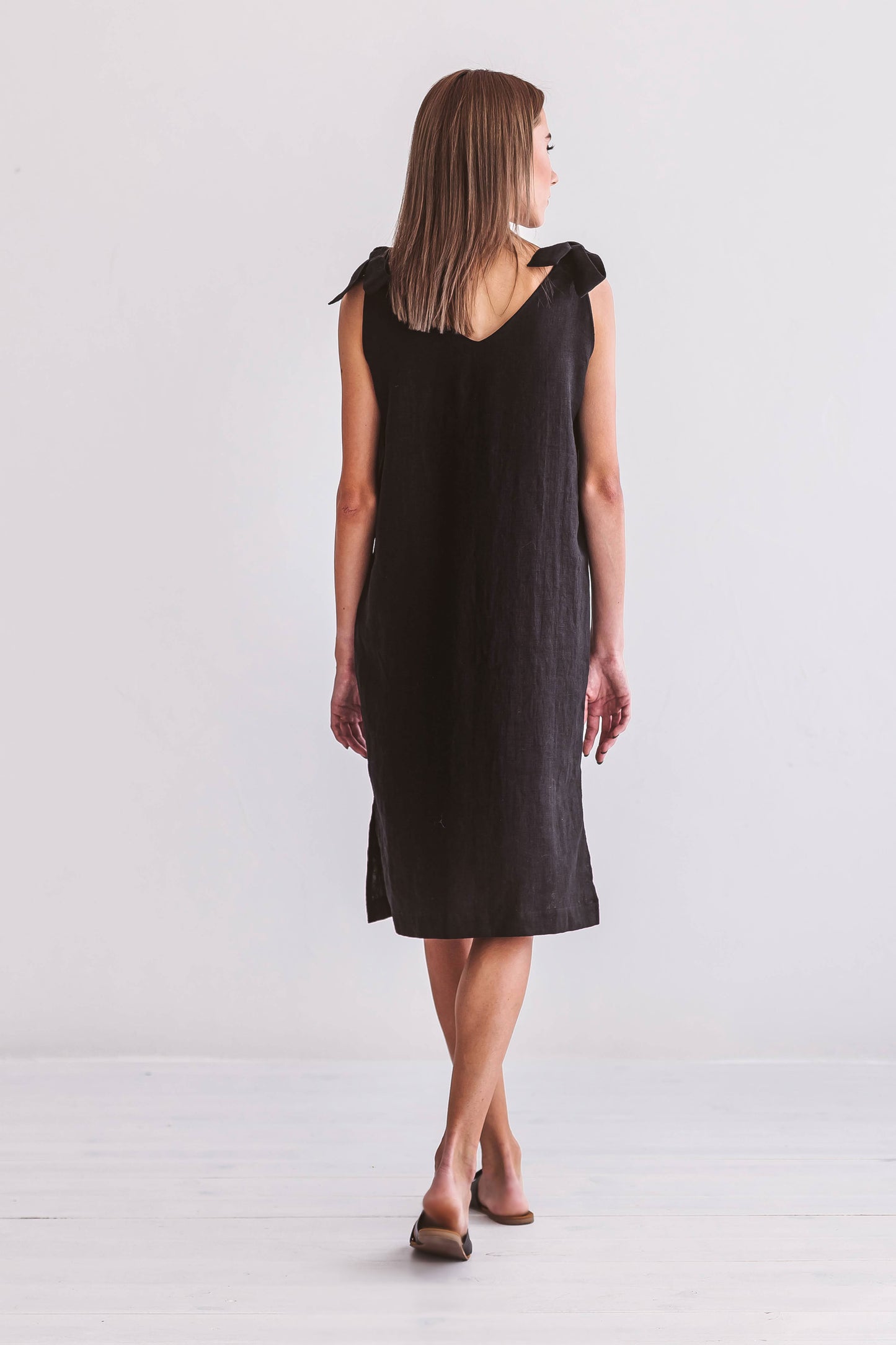 Black linen dress close-up detail showing shoulder ties and linen texture, handmade linen dress slow fashion