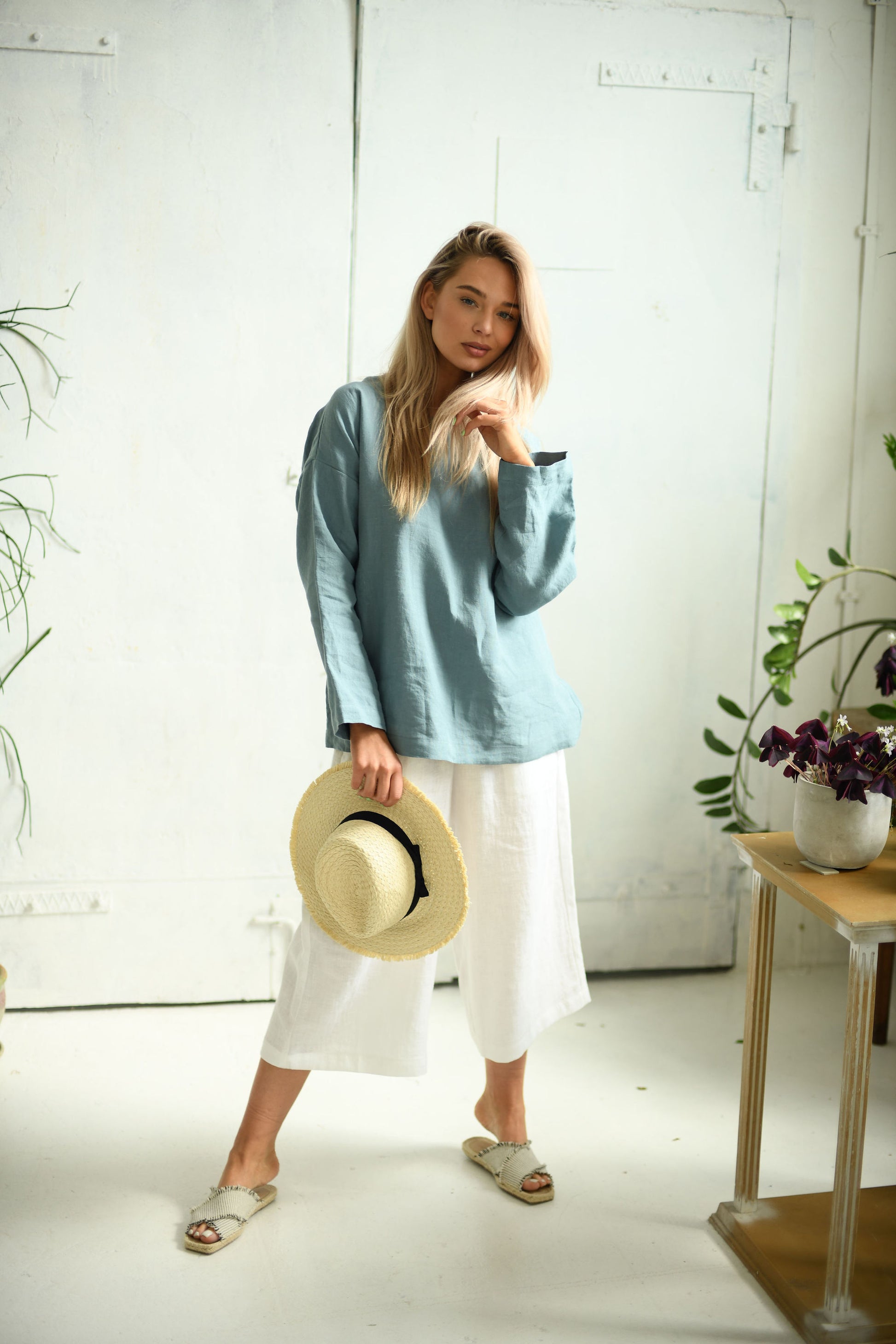White linen pants relaxed standing pose with hat showing comfortable fit, handmade linen pants slow fashion