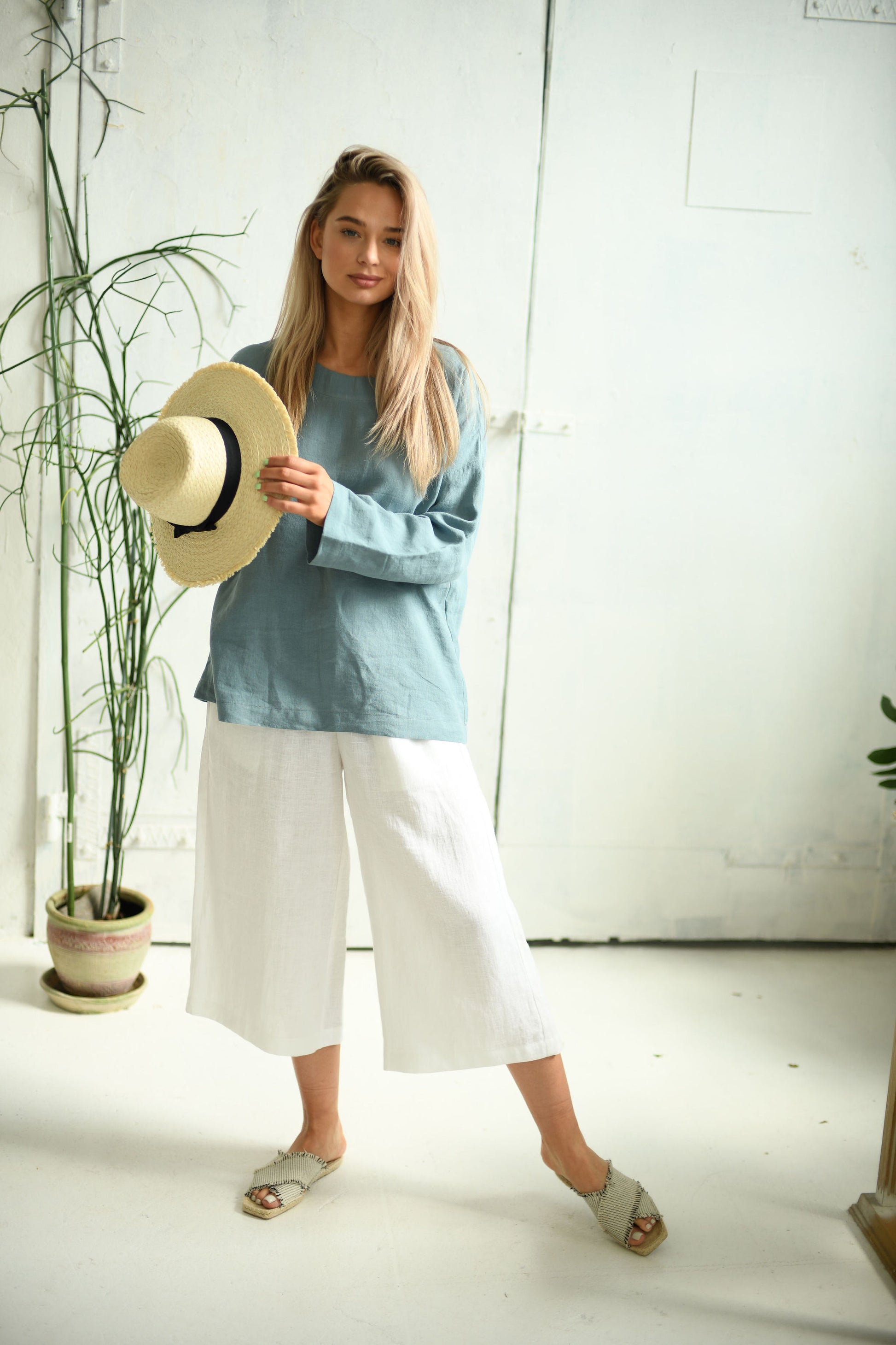 White linen pants side view standing indoors showing wide-leg shape, handmade linen pants slow fashion